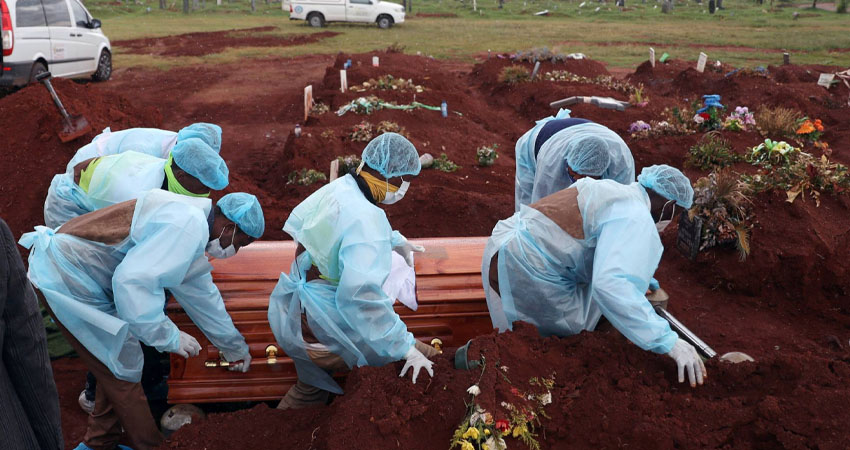 Trabajadores funerarios con equipo de protección personal llevan un ataúd durante el entierro de una víctima de covid-19. Foto: Cortesía/El País. Trabajadores funerarios con equipo de protección personal llevan un ataúd durante el entierro de una víctima de covid-19. Foto: Cortesía/El País.